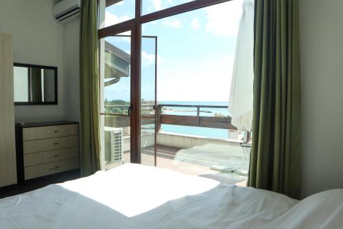 a bedroom with a bed and a view of the ocean at White Coast Beach Apartments in Kavarna