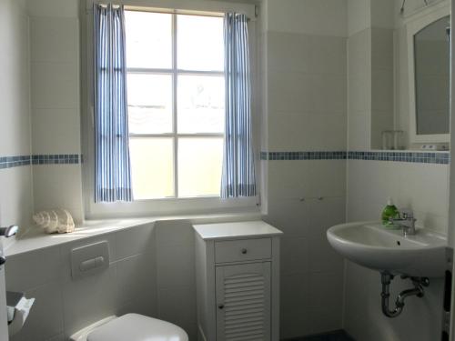 La salle de bains est pourvue d'un lavabo, de toilettes et d'une fenêtre. dans l'établissement Wiesenstraße 55 Whg 1 - Meeresbrise, à Zingst