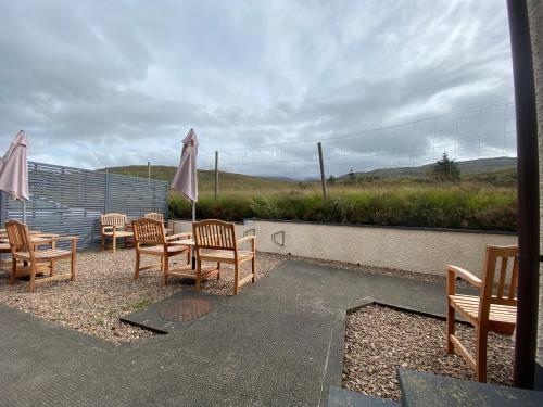a patio with chairs and tables and an umbrella at Highland Stays - Ben View Double Rooms in Fort William