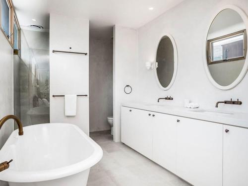 a white bathroom with a sink and a mirror at Driftwood Three At Clarkes Beach in Byron Bay