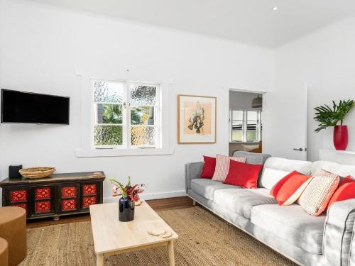 a living room with a couch and a table at Alkira - Boutique cottage - Walk to Clarkes Beach in Byron Bay