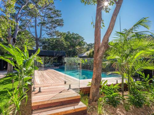 a house with a swimming pool and a wooden deck at Tallowood - luxury beach house with pool & studio in Suffolk Park