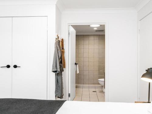 una camera da letto con pareti bianche e un bagno con servizi igienici di Le Viti a Byron Bay