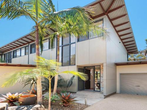 a house with palm trees in front of it at Your Luxury Escape - Kiah 11 Beach House Ocean views in Byron Bay