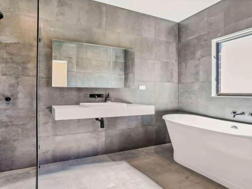 a bathroom with a sink and a tub and a mirror at Pauls Farmhouse in Newrybar