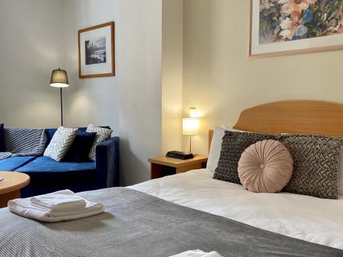- une chambre avec un lit et un canapé bleu dans l'établissement 203 Cute As A Button Wkitchen For 2cbd, à Perth