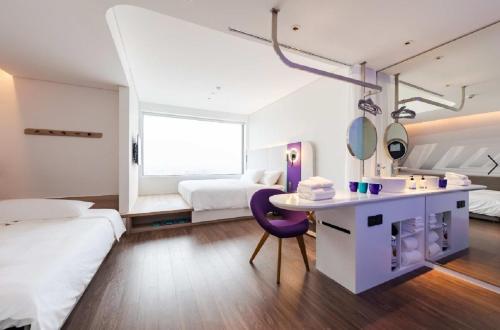ein Hotelzimmer mit 2 Betten, einem Waschtisch und einem lila Stuhl in der Unterkunft SOJO Hotel Thai Binh in Thái Bình