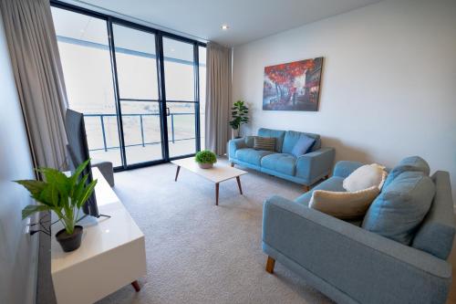 a living room with a blue couch and a tv at Trendy, Self Contained Inner City Apartment in Wagga Wagga