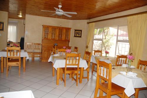a dining room with white tables and wooden chairs at Purple Olive Guest House in Pretoria