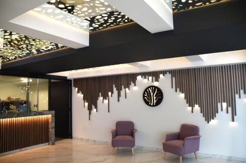 a lobby with two chairs and a clock on the wall at Amarterra Hotel Boutique in Mexico City