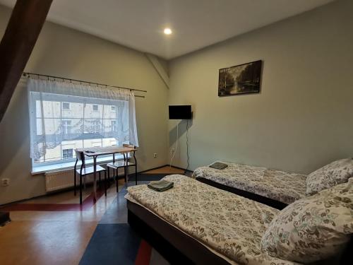 a bedroom with two beds and a table and a window at Hostel "Na Bocianowie" in Bydgoszcz