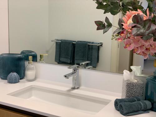 a bathroom sink with a large mirror and a sink at Mariner's Cove ~ Luxe Waterfront Apartment in Mindarie