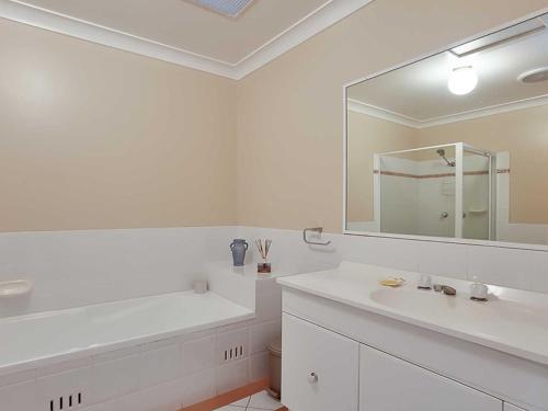a white bathroom with a sink and a mirror at Sunset on Birubi pet friendly air con water views WI-FI and outdoor spa in Anna Bay
