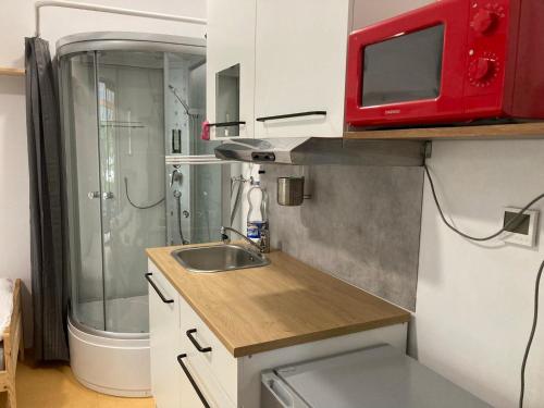 una pequeña cocina con fregadero y microondas rojo en KuK Račice - mini apartman, en Račice