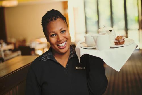 a woman holding a plate with a cupcake on it at Premier Resort Mpongo Private Game Reserve in Macleantown