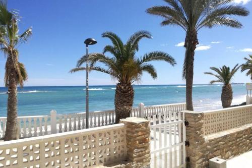 a white fence and palm trees on the beach at CHALET A 5 METROS DEL MAR.Wifi gratis in Murcia