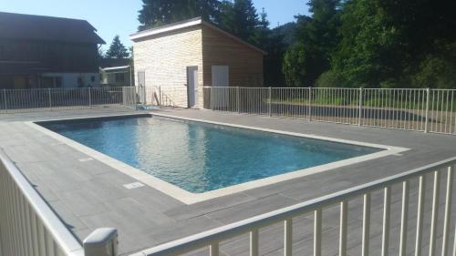 ein Pool in einem Garten mit einem Zaun in der Unterkunft Tiny House - Cottages - Mobilhomes - Camping Les Granges Bas in Gérardmer