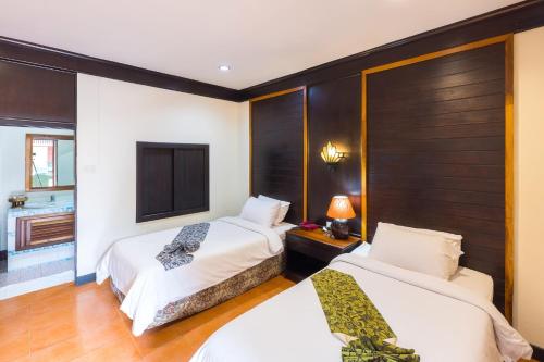 Habitación de hotel con 2 camas y TV en เฮือนคำรีสอร์ท บูติค โฮเทล แม่สาย เชียงราย en Chiang Rai
