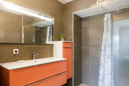 La salle de bains orange est pourvue d'un lavabo et d'une douche. dans l'établissement Mandelieu 404 YourHostHelper, à Mandelieu-la-Napoule