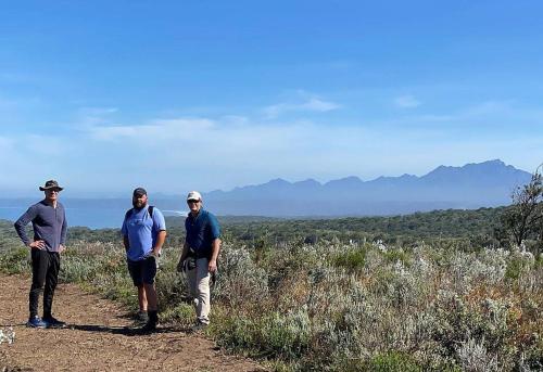 a group of three men standing on a dirt trail at Simbavati Fynbos on Sea in Sedgefield