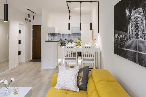 a living room with a yellow couch and a kitchen at Divat Apartments - Central Smart Homes in Győr