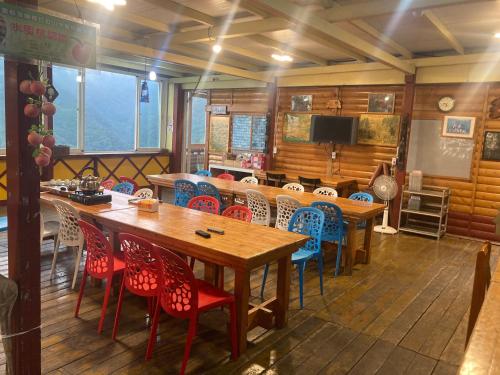 a dining room with wooden tables and colorful chairs at Junlin Holiday Farm in Hualing