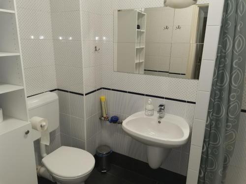 a white bathroom with a toilet and a sink at Zoli Apartmanok-Balcony Kölcsey 32 in Hajdúszoboszló