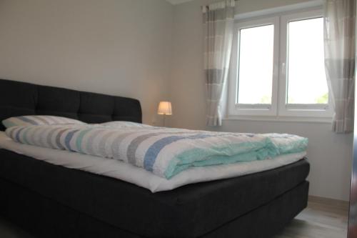 a black couch with a blanket on it in a bedroom at Meerblick Fehmarnsund 1 - direkt am Strand in Fehmarnsund