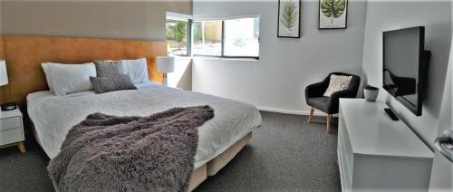 a bedroom with a bed and a television and a chair at Moonah Links - Apartment 43 in Fingal