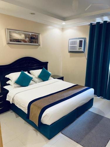 ein Schlafzimmer mit einem großen Bett mit blauen Kissen in der Unterkunft بنان للشقق المفروشة in Tabuk
