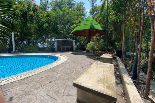 a swimming pool with a green umbrella next to a pool at Maxxim Rainforest Retreat - Rawang in Rawang