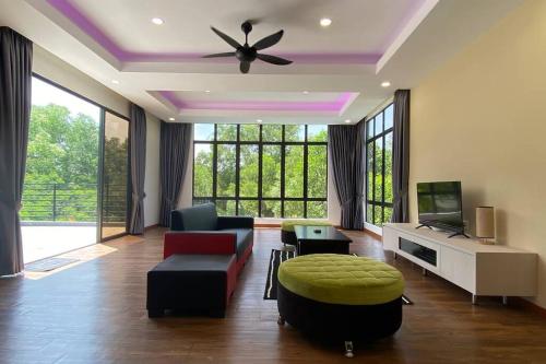 a living room with a ceiling fan and a couch and a tv at Maxxim Rainforest Retreat - Rawang in Rawang