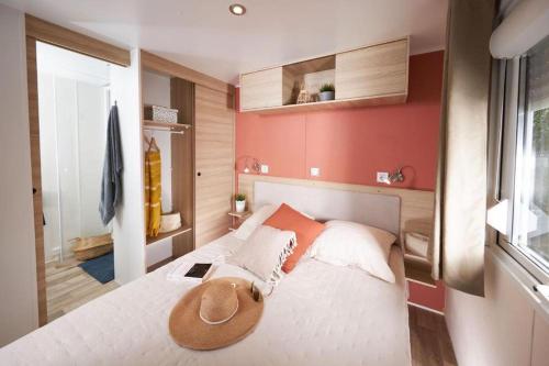 una camera da letto con un letto con un cappello sopra di Mobile home 3 chambres 2 salles de bains dans camping 4 étoiles aux charmettes MH k168 a Les Mathes