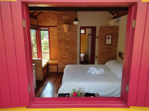 a bedroom with a large pink window with a bed at Chalé Canto da Colina-Lumiar in Lumiar