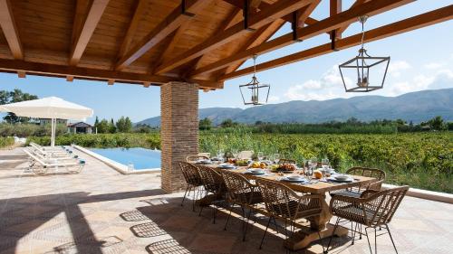 a dining table on a patio with a view of a vineyard at Aneli Luxury Villas - Villa Semeli in Zakynthos Town