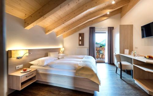 a bedroom with a large white bed and a kitchen at Hotel Gasthaus Post in Campo di Trens