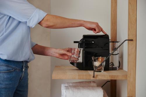 a man is holding a cup next to a toaster at Edgar Guesthouse in Ghent
