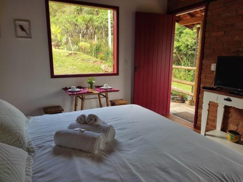 a bedroom with a bed with towels on it at Chalé Canto da Colina-Lumiar in Lumiar