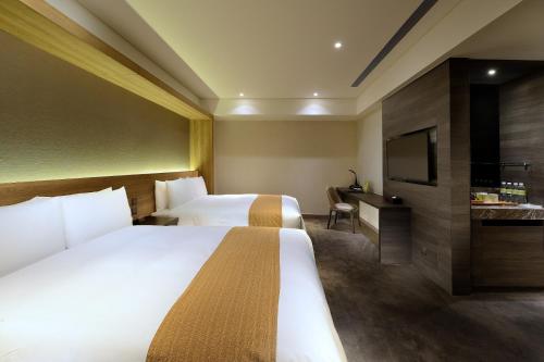 a hotel room with two beds and a television at Hualien Holiday Hotel in Hualien City