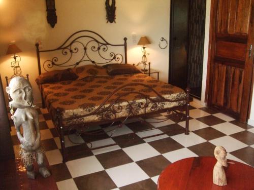 a bedroom with a bed and a checkered floor at Maison Couleur Passion in Nianing