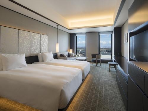 千歳市にあるポルトム インターナショナル 北海道のベッド2台、薄型テレビが備わるホテルルームです。
