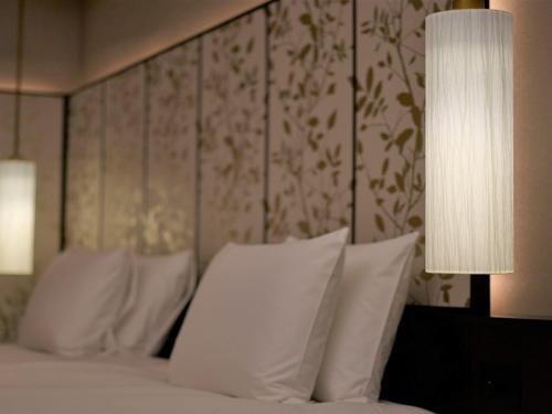 a bedroom with a bed with white pillows and a lamp at Portom International Hokkaido in Chitose
