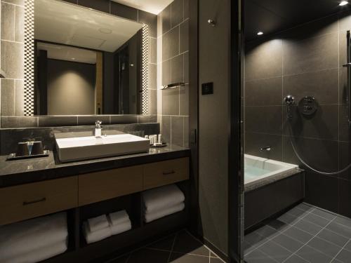 a bathroom with a sink and a tub and a mirror at Portom International Hokkaido in Chitose
