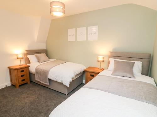 two beds in a bedroom with two lamps on tables at 2 Morton Cottages in Preston