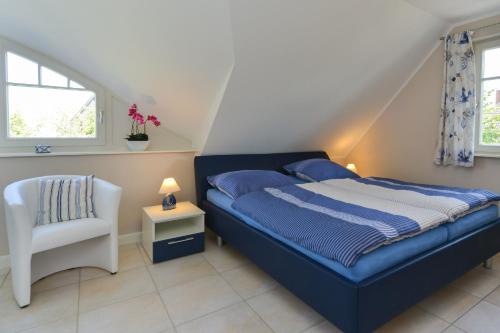a bedroom with a blue bed and a white chair at Ferienhaus Strandschnecke in Zingst