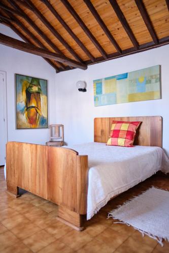 a bedroom with a bed with a wooden headboard at Casa D'Alfaias in Nordeste