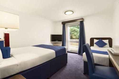 a hotel room with two beds and a window at Ramada Oxford in Waterstock