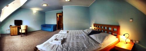 a bedroom with a large bed and a blue wall at Hotel Farma Vysoká in Chrastava