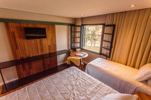 a bedroom with two beds and a window at Umani Pousada in Bento Gonçalves