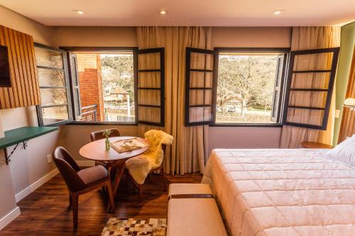 a bedroom with a bed and a table and window at Umani Pousada in Bento Gonçalves